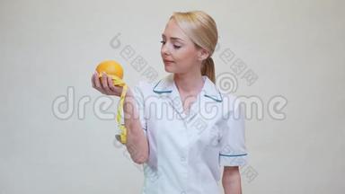 营养学家医生健康的生活方式理念-拿着橘子水果和量胶带